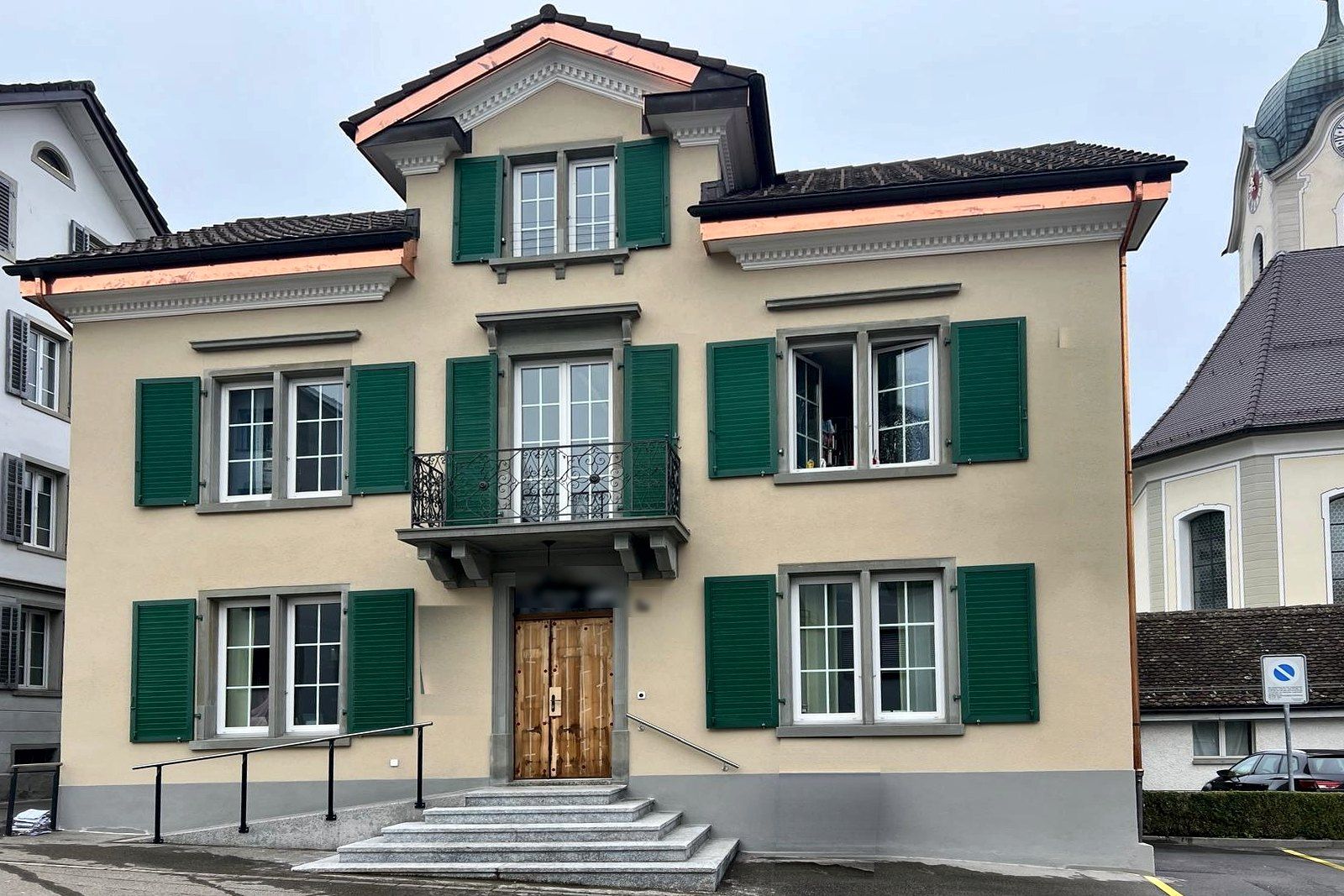 Historische Villa mit grünen Jalousieläden, Balkon mit Schmiedeeisengeländer und neuen Kupferblechen