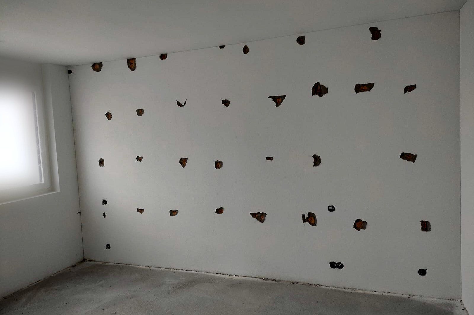 Zimmerwand mit Ausbrüchen der Gerüstanker im Raster