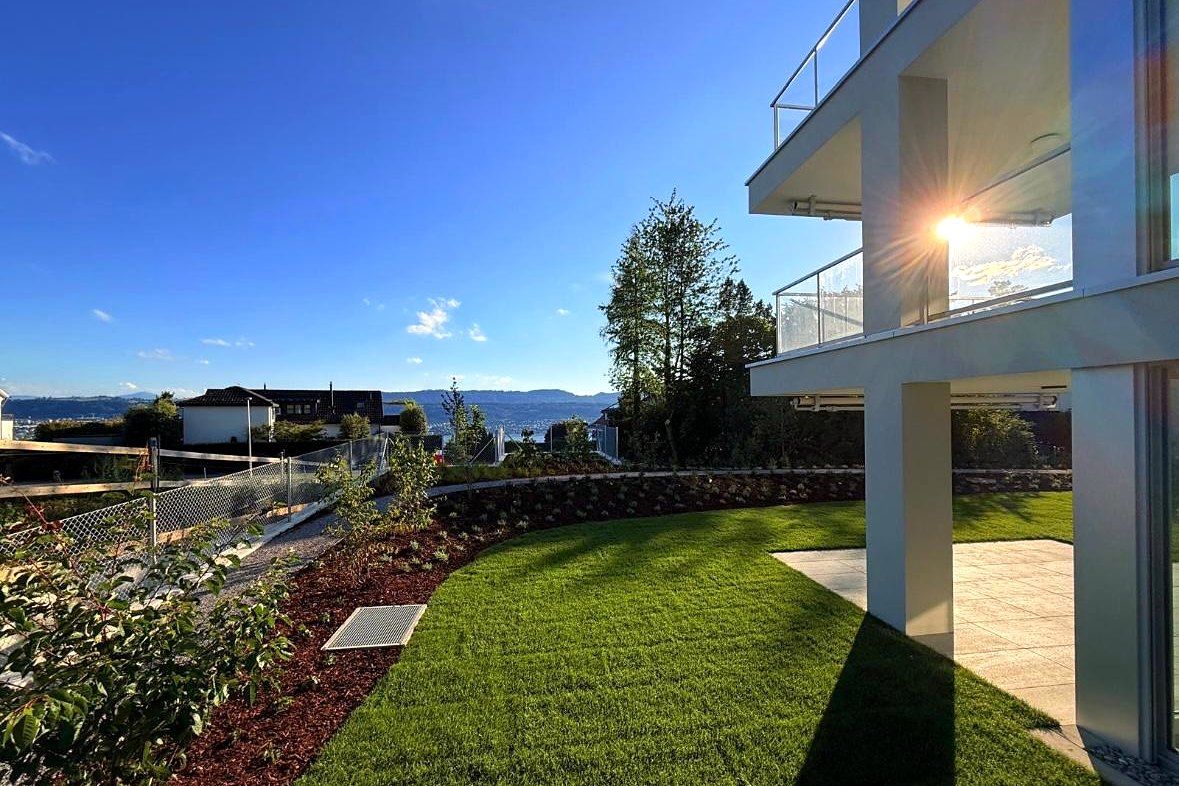Gartenseite des Mehrfamilienhauses im Abendlicht mit Blick über den See