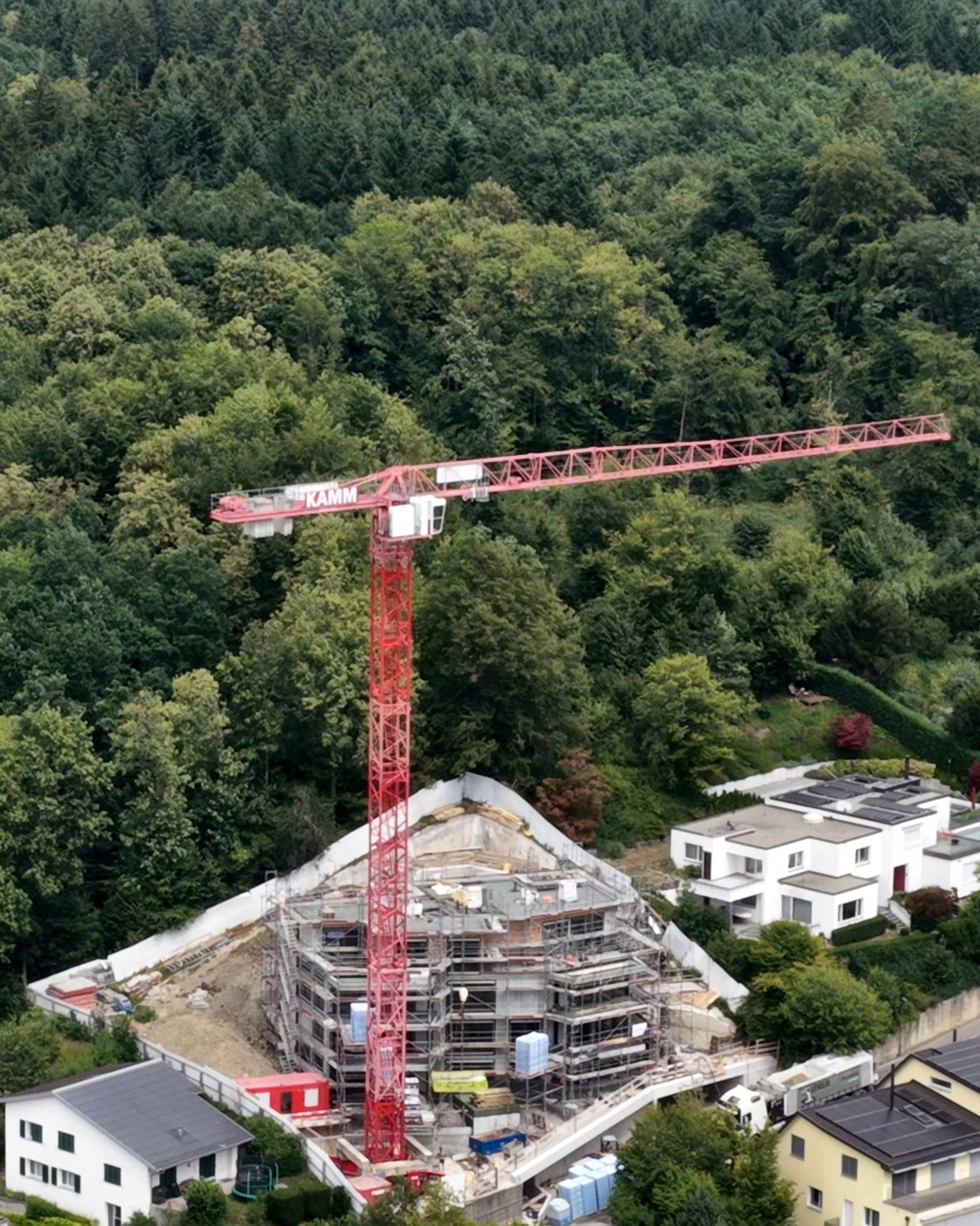Drohnenbild: Kran und Rohbau am Hang vor dem Wald