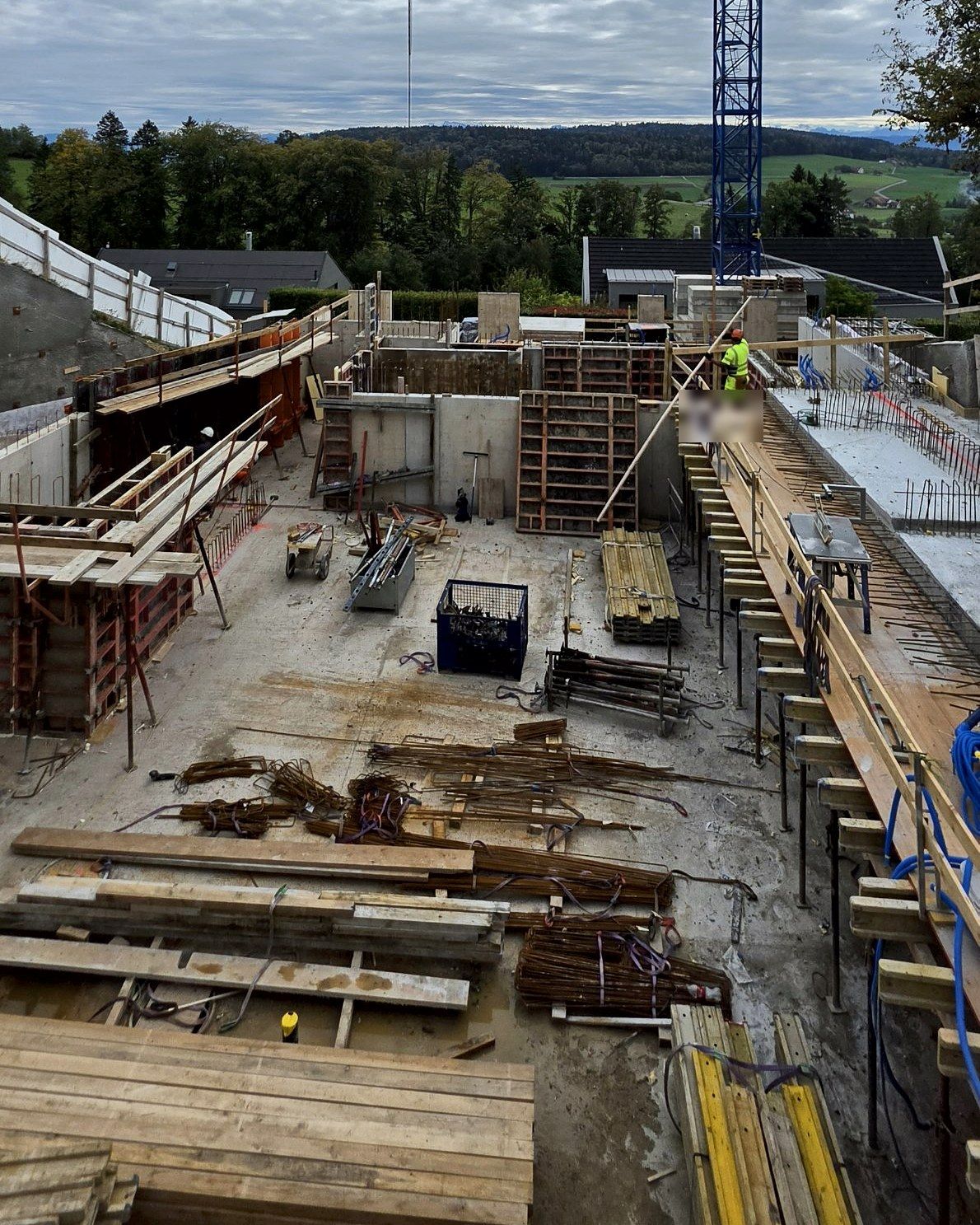 View over the basement with formwork and rebar, crane at the edge