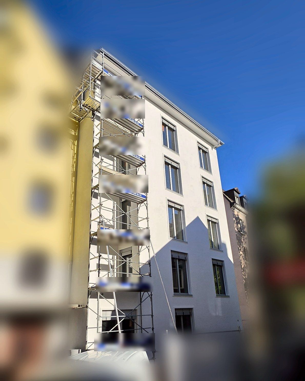 Narrow façade with scaffold tower, neighbouring houses blurred