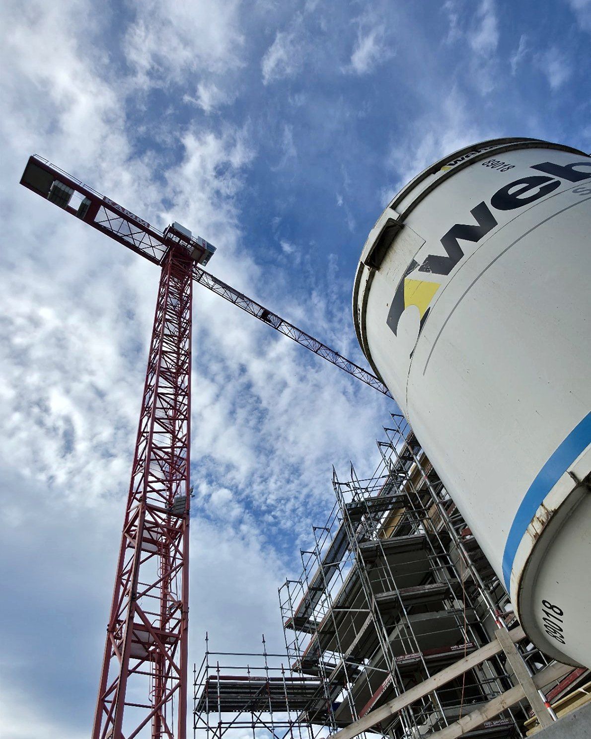 Turmdrehkran und Silo vor dem eingerüsteten Bau