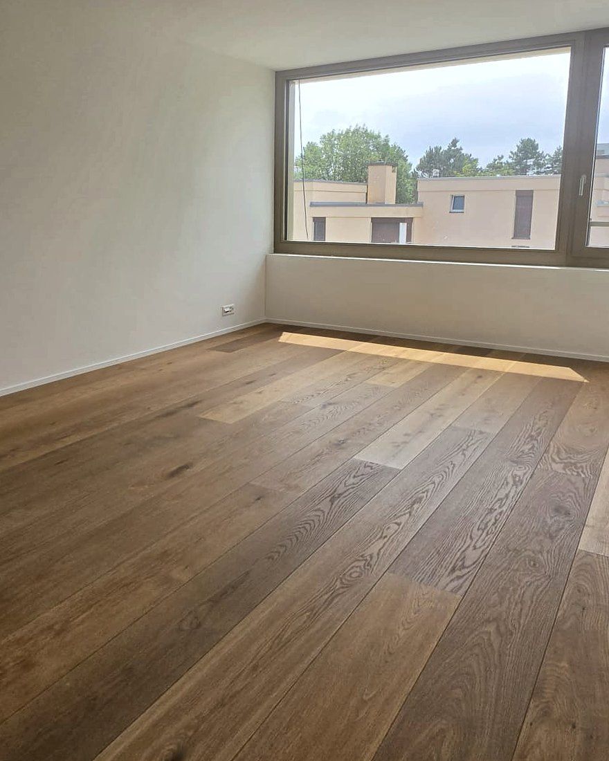 Zimmer mit grossem Fenster und Eichenparkett