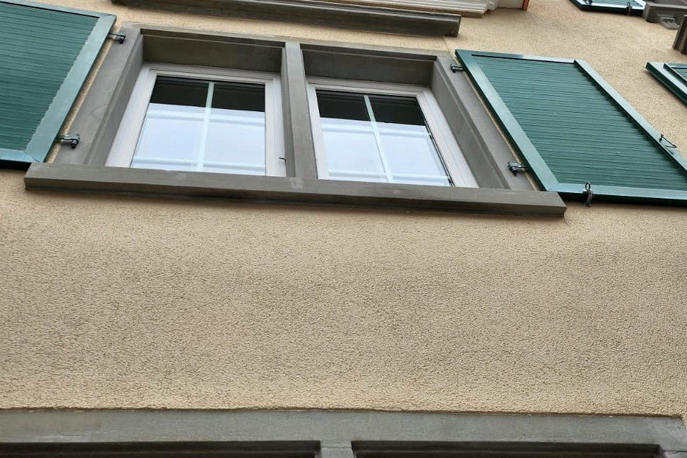 Fenster mit Sandsteingewände und grünen Läden von unten