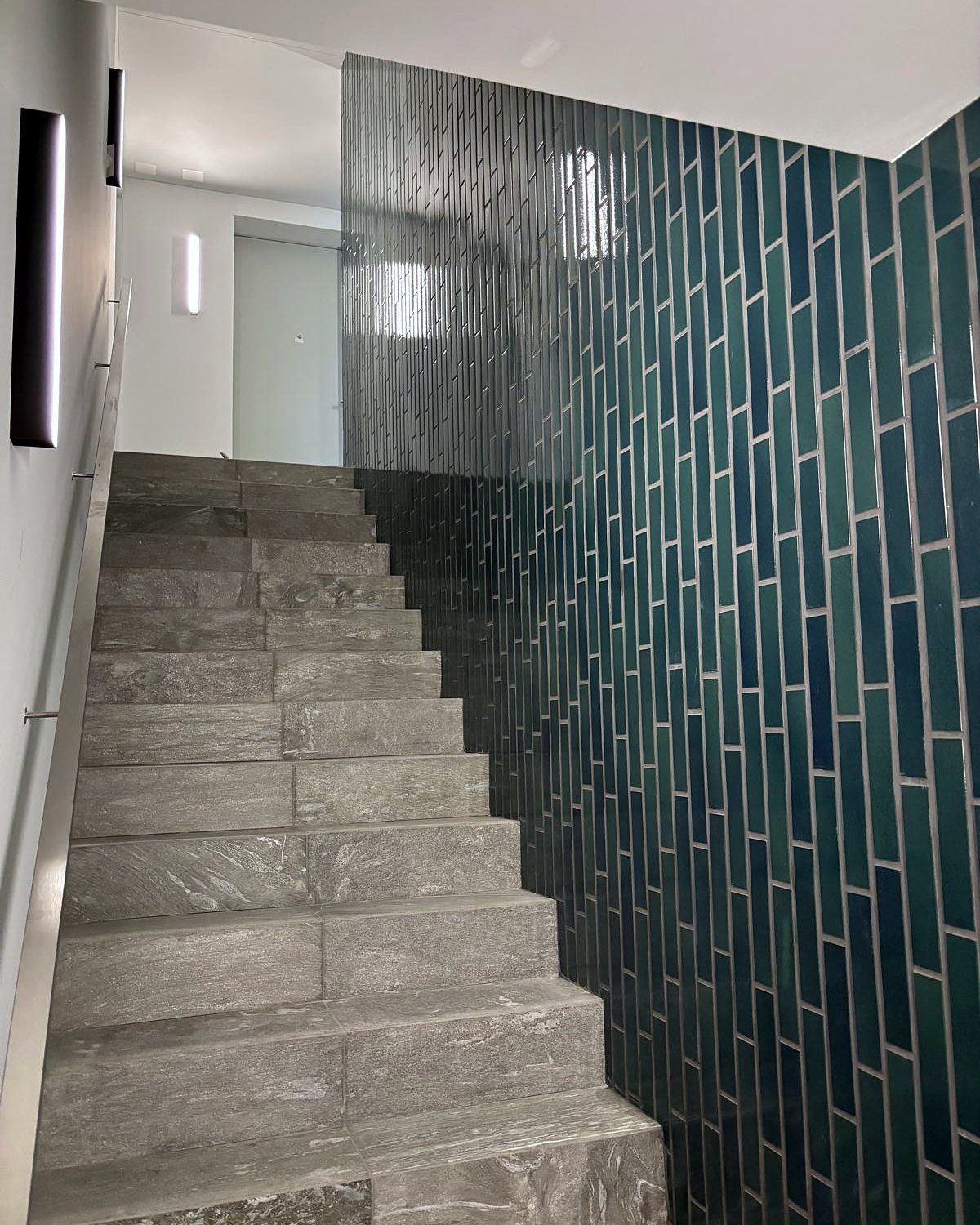 Treppe mit Natursteinbelag und grüner Plattenwand
