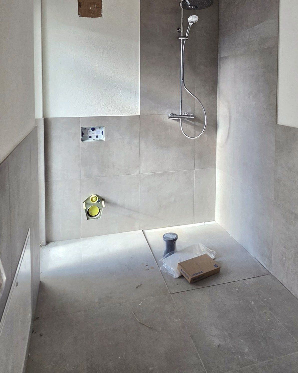 Bathroom with large-format tiles and rain shower, fit-out underway