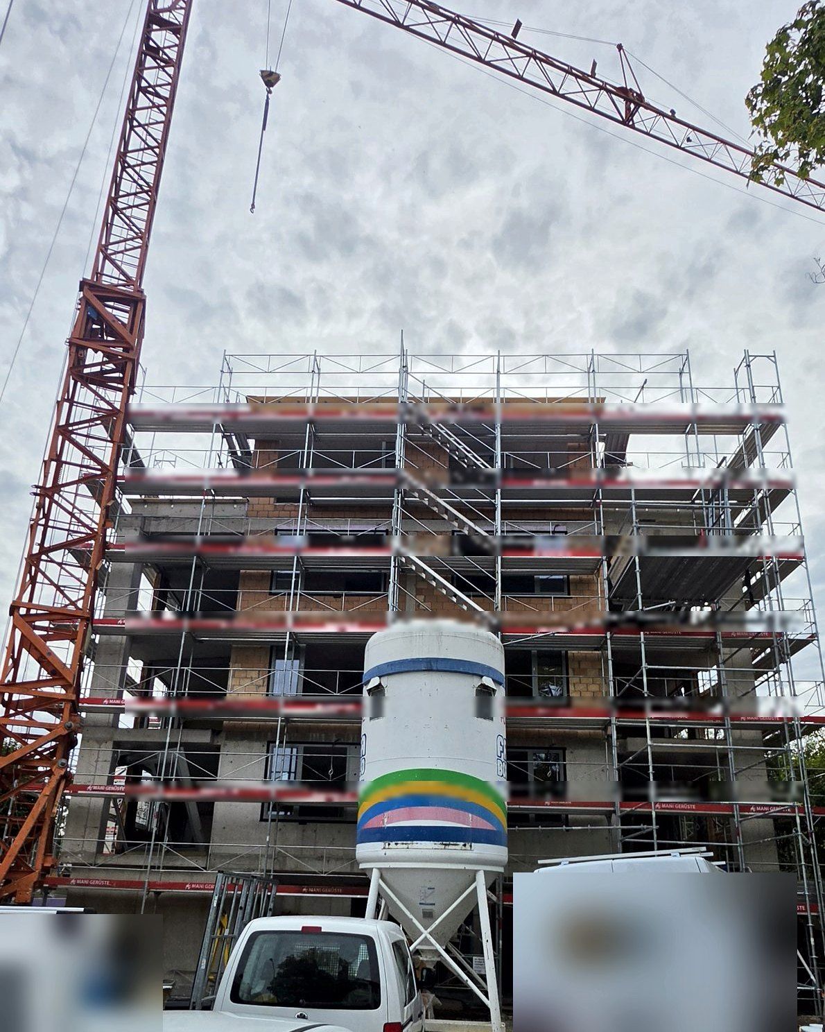 Rohbau im Gerüst mit Kran und Silo, Firmenfahrzeuge unkenntlich gemacht