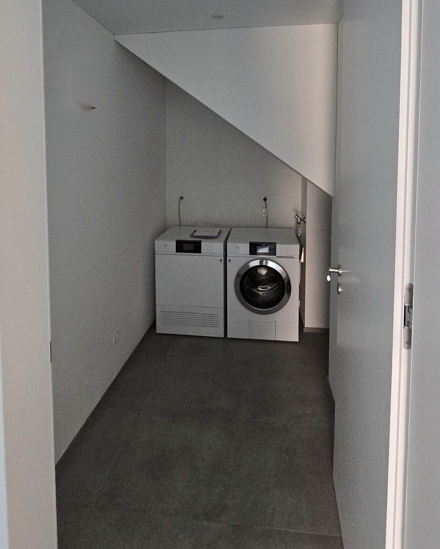 Waschmaschine und Tumbler in einem Raum unter der Treppe