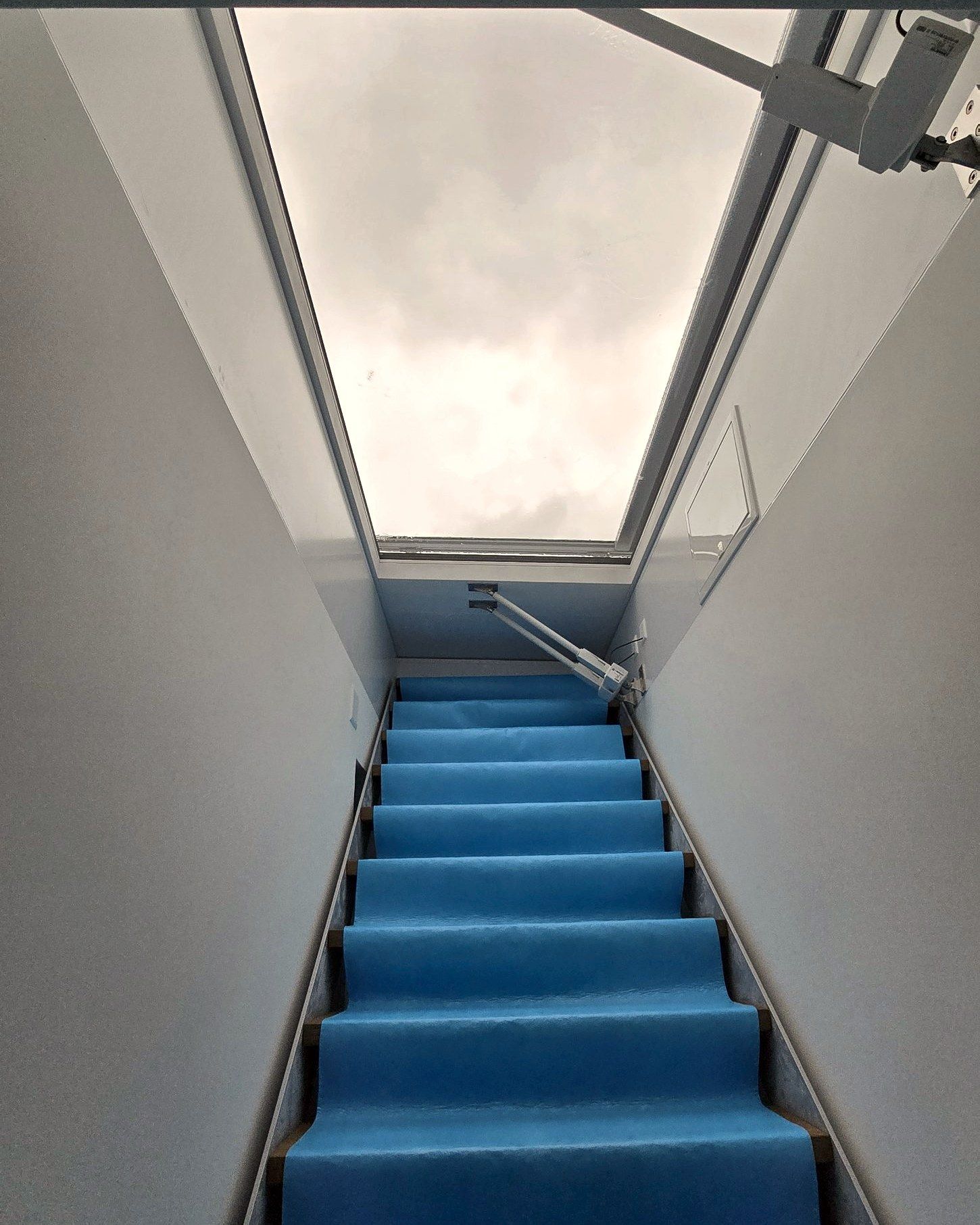 Treppe mit abgedeckten Stufen zu einer offenen Dachluke